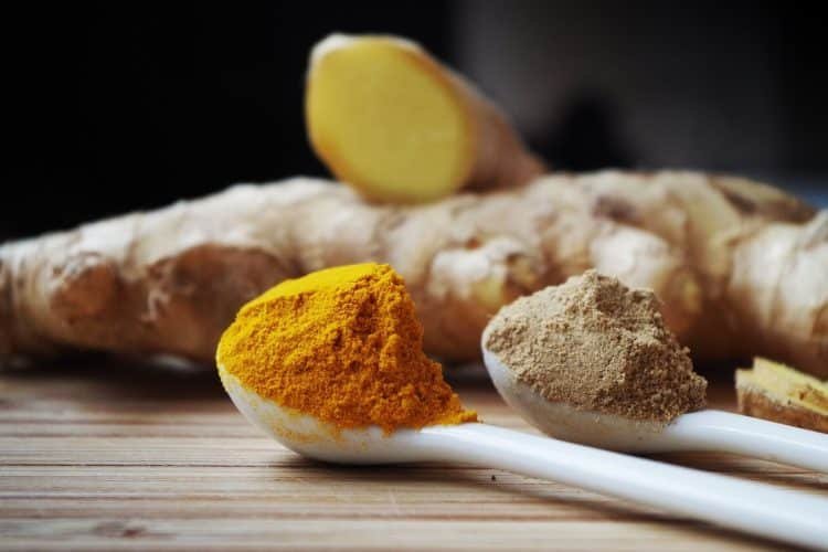 Turmeric powder with a slice of turmeric root